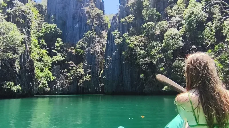 Guest kayaking through a turquoise lagoon between limestone cliffs in Palawan